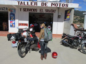 Hilary watches the owner of "El Shaday Moto Taller" install a piece from a used Honda to El Herocito.