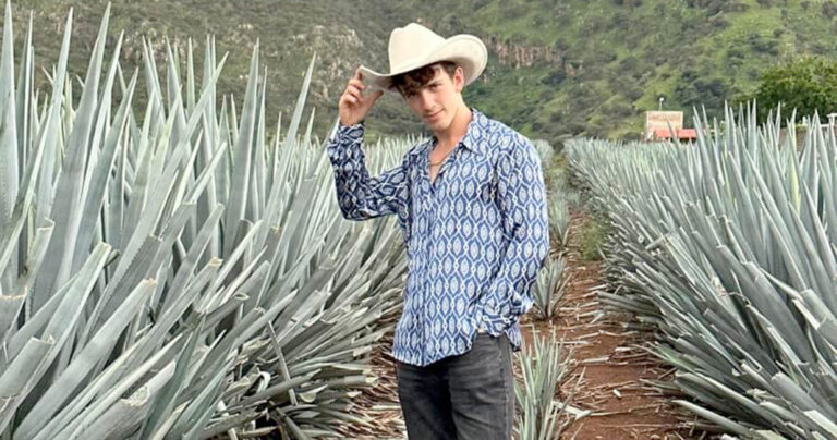 Man standing in field wearing cowboy hat