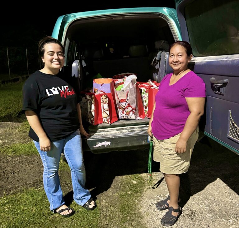 two people standing in front of a truck that has bags in it.