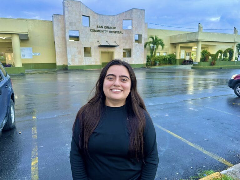 person smiling in front of a hospital